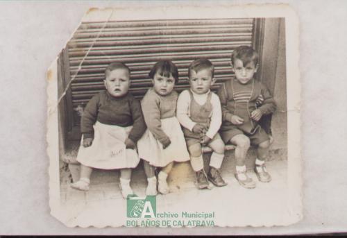 Niños sentados en puerta de comercio de Elvira de Miguel, año 1958
